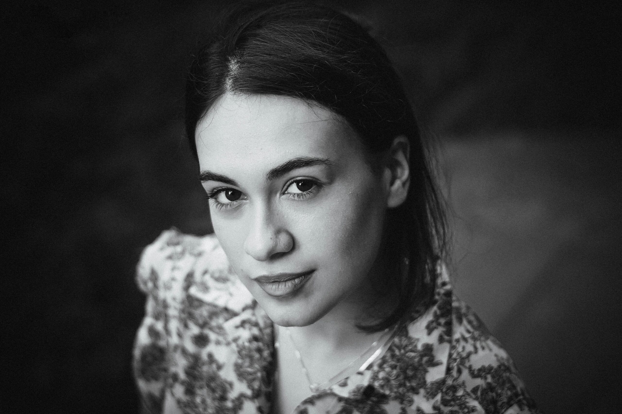 Elegant black and white portrait of a young woman with direct gaze and floral attire.